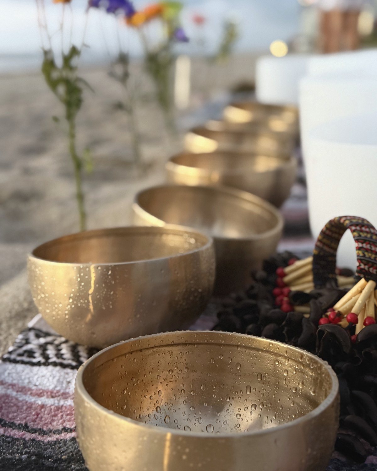 A bowl in the foreground, more bowls and a mallet behind, flowers blurred